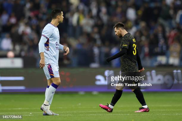 Lionel Messi of Paris Saint-Germain walks past Cristiano Ronaldo of Riyadh XI after scoring the side's first goal during the Winter Tour 2023...