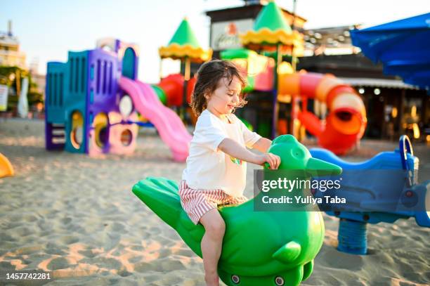 ビーチの遊び場で遊ぶ幸せな少女 - rimini ストックフォトと画像