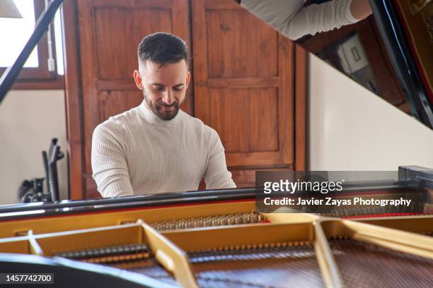 young adult playing grand piano at home - pianist front stock pictures, royalty-free photos & images