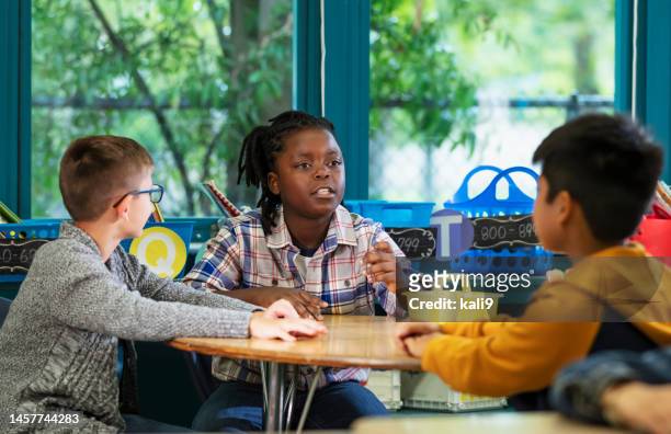 tre ragazzi multirazziali della scuola elementare in classe - bambini seduti in cerchio foto e immagini stock