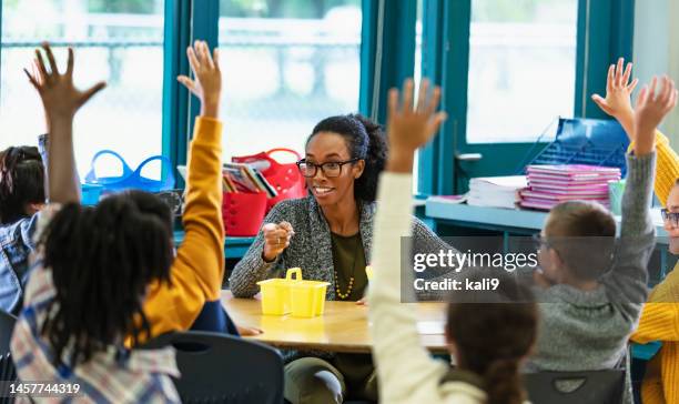 teacher in classroom points to student raising hand - teacher in front of class stock pictures, royalty-free photos & images