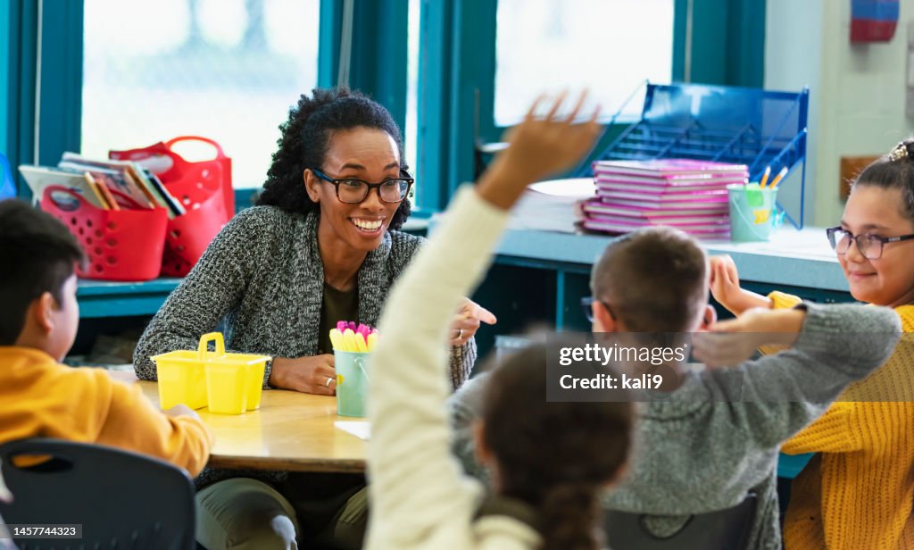 Teacher in classroom points to student raising hand