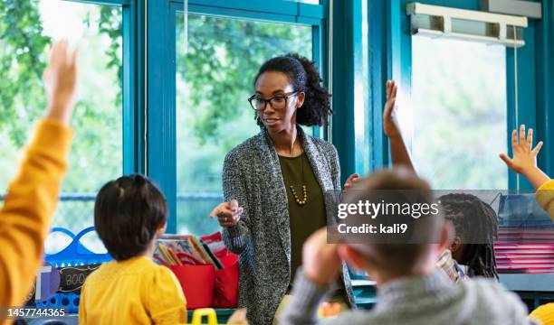 teacher in classroom points to student raising hand - teacher in front of class stock pictures, royalty-free photos & images