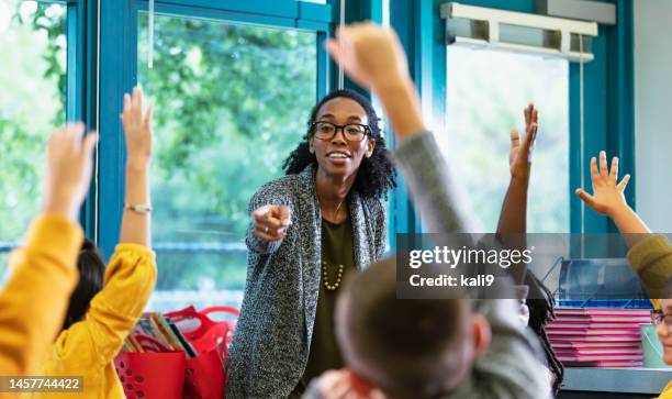 lehrer im klassenzimmer weist darauf hin, dass der schüler die hand hebt - children in classroom stock-fotos und bilder