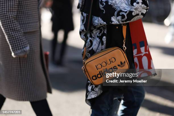 Fashion week guest seen wearing a patterned jacket and an orange Gucci x Adidas bag before the Bluemarble show during Paris Fashion Week Menswear...