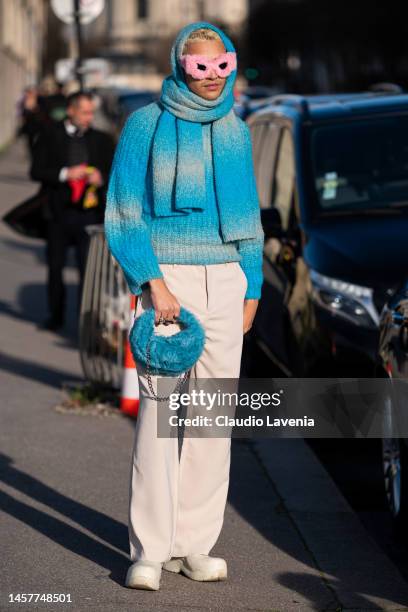 Guest wears a light blue jumper, light blue big scarf, white pants, light blue fur bag and pink fur sunglasses, outside Givenchy, during Paris...