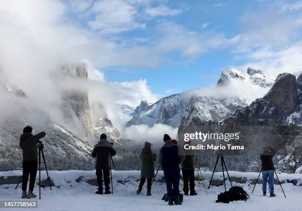 Photographers gather at a viewpoint overlooking Yosemite Valley as clouds begin to clear from the last of a series of atmospheric river storms to hit...