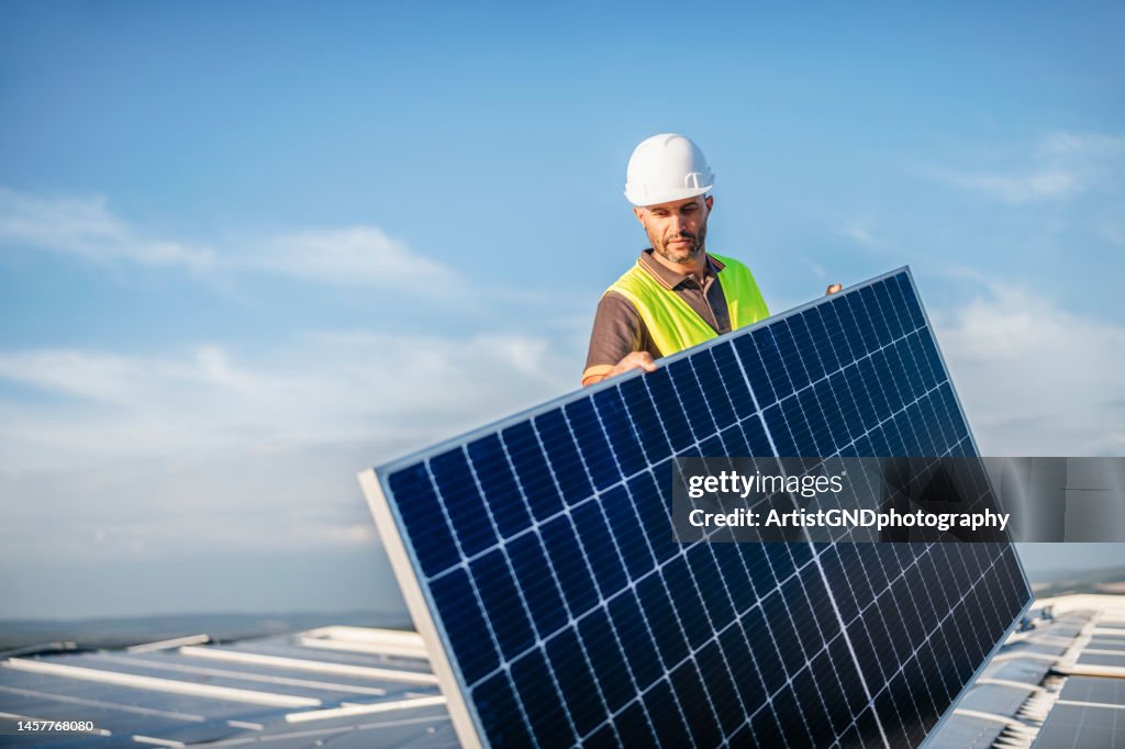 Arbeiter mit Sonnenkollektor auf dem Dach.