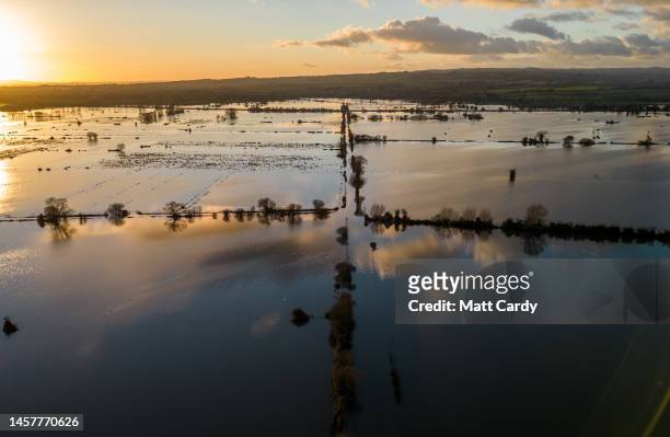 The sun sets over flood water surrounds the A361 road which has been closed to vehicles because of widespread flooding of the Somerset Levels on...