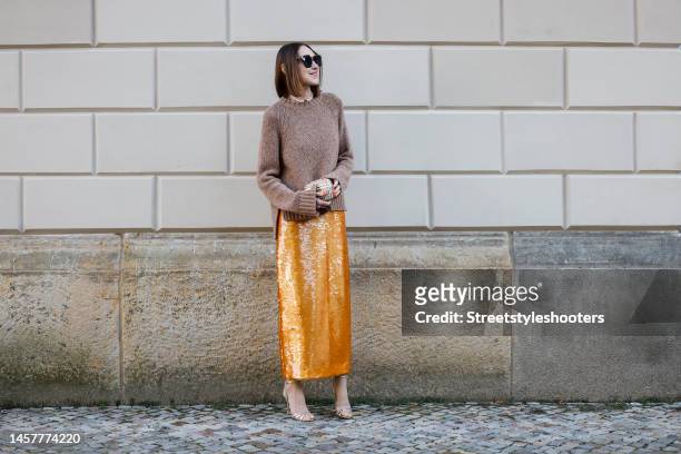Influencer Annette Weber, wearing a orange colored sequin skirt by Gembalies, a light brown mottled cashmere pullover by Gembalies, a pearl necklace...
