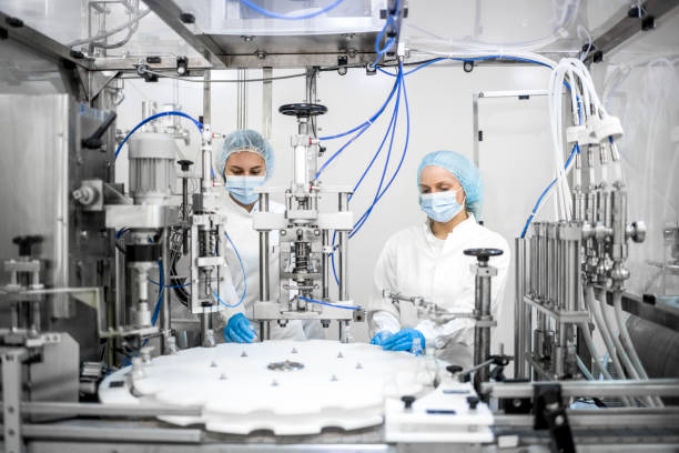 Two people in hairnets and masks operating a biomanufacturing machine