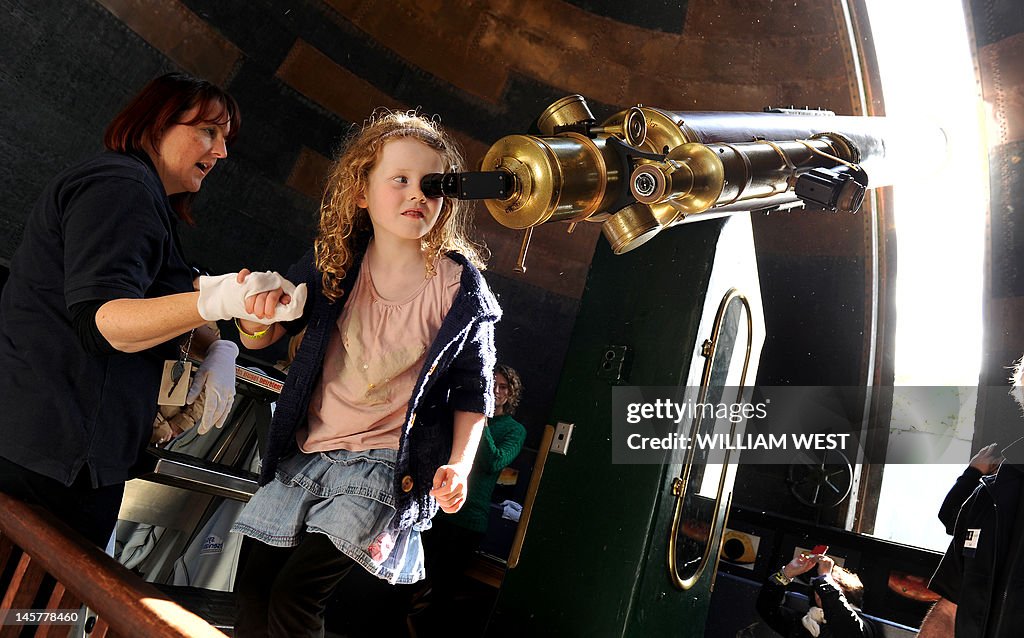 A young girl looks through a telescope t