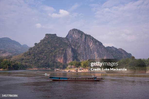 long boat passes by phahung cliff - pak ou caves stock pictures, royalty-free photos & images
