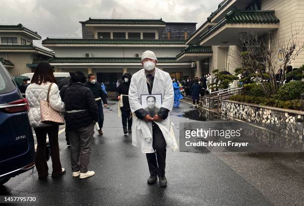 Mourner carries a photo of a loved one as he wears traditional white funeral clothing at funeral home on January 14, 2023 in Shanghai, China. Chinas...