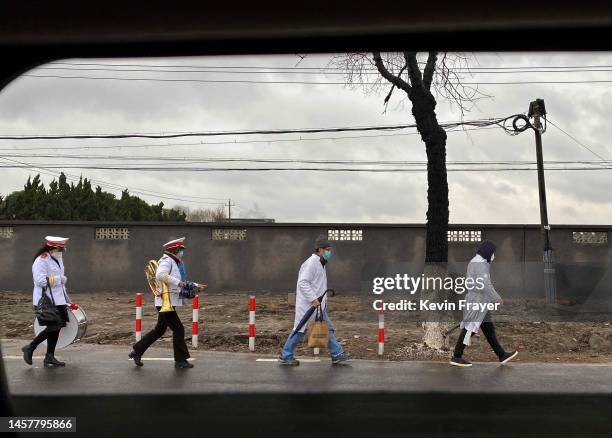 Members of a funeral band and mourners walk along a road as they leave a funeral home on January 14, 2023 in Shanghai, China.Chinas health care...