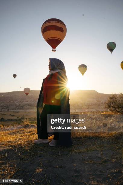 seniorin genießt den sonnenaufgang mit blick auf den heißen ballon in göreme - hot middle eastern women stock-fotos und bilder