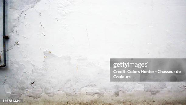 weathered and peeling white paint on concrete wall with metal pipe in london - boundary wall stock pictures, royalty-free photos & images