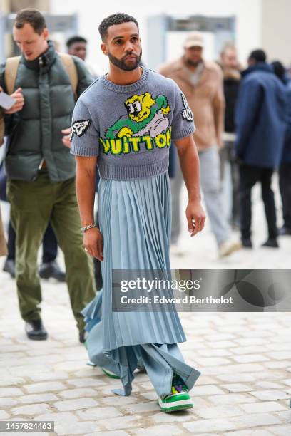 Lucien Laviscount wears a gray with yellow / green / white print pattern wool short sleeves cropped t-shirt from Louis Vuitton, a blue gray pleated /...