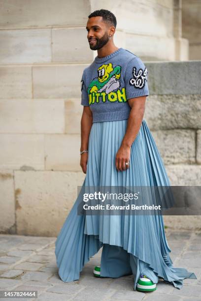 Lucien Laviscount wears a gray with yellow / green / white print pattern wool short sleeves cropped t-shirt from Louis Vuitton, a blue gray pleated /...