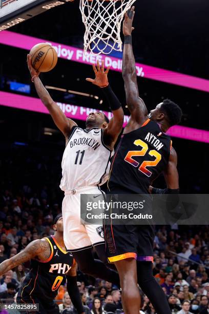 Kyrie Irving of the Brooklyn Nets drives to the basket on Deandre Ayton of the Phoenix Suns during the second half at Footprint Center on January 19,...