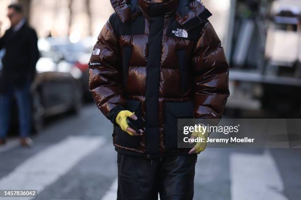 Fashion week guest seen wearing a jacket by The North Face, yellow Louis Vuitton gloves, leather shorts and long wide jeans and white sneaker before...