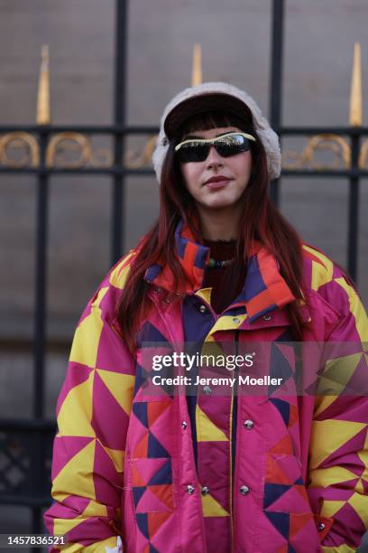 Fashion week guest seen wearing a pink and yellow patterned matching look with a Gucci cap and fluffy earmuffs, purple crocs and shades before the...