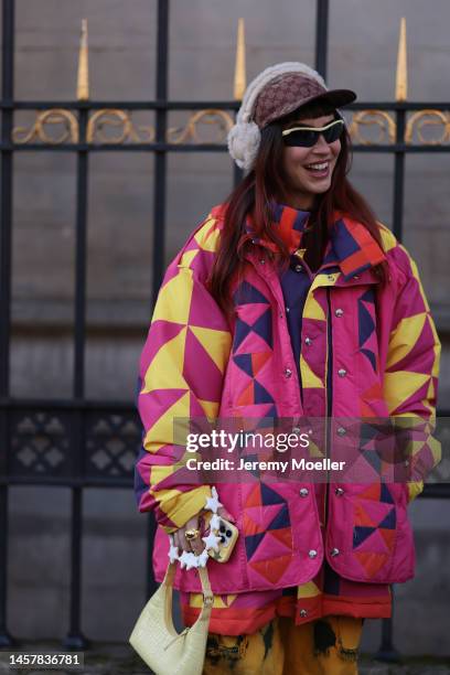 Fashion week guest seen wearing a pink and yellow patterned matching look with a Gucci cap and fluffy earmuffs, purple crocs and shades before the...