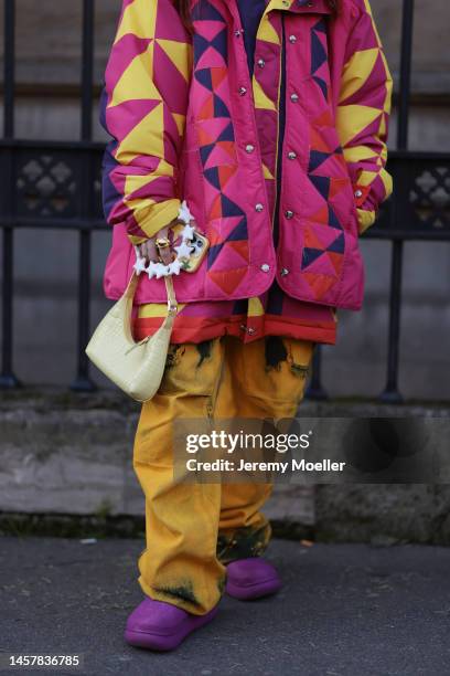 Fashion week guest seen wearing a pink and yellow patterned matching look with a Gucci cap and fluffy earmuffs, purple crocs and shades before the...