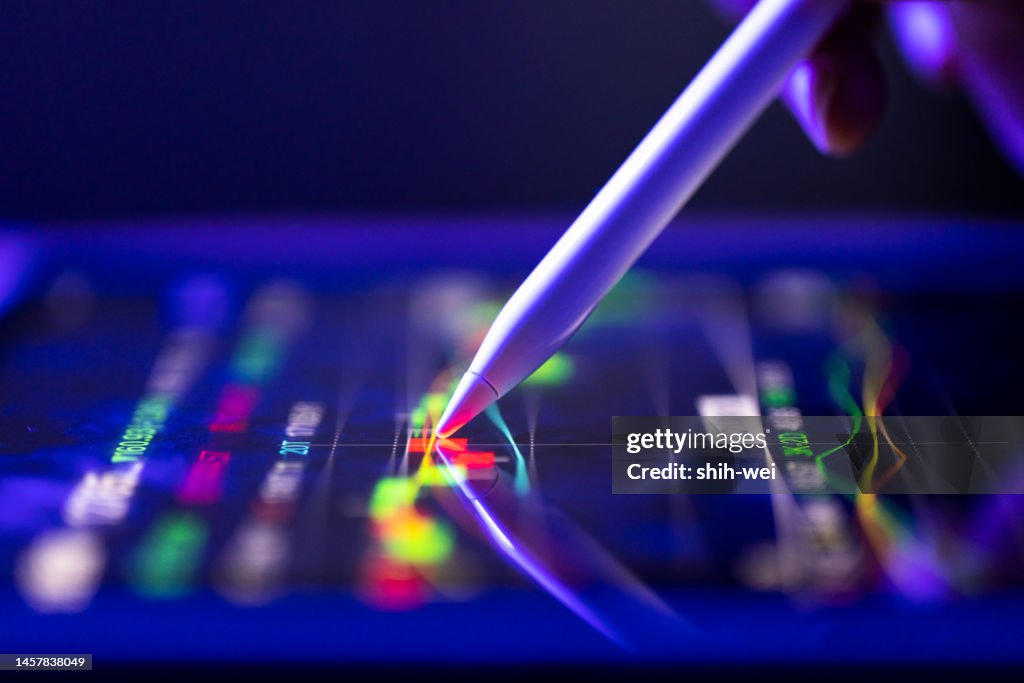 A business person tracking the technical movement of a stock chart on a computer screen.