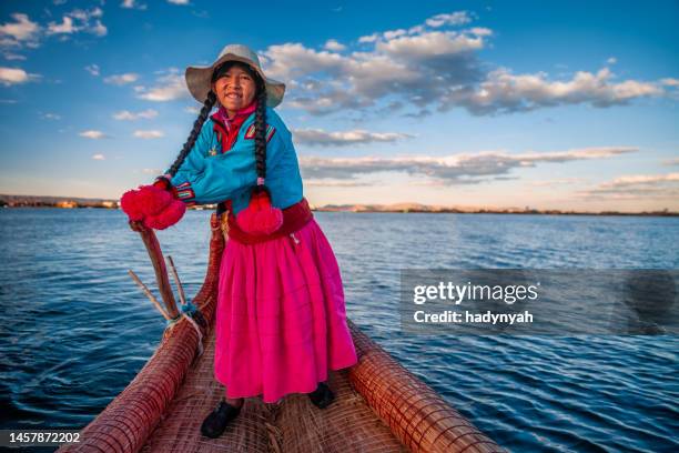 peruvian woman sailing between uros floating islands, lake tititcaca - uros stock pictures, royalty-free photos & images