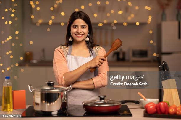 portrait of a young woman cooking food in the kitchen stock photo - indian chef stock pictures, royalty-free photos & images