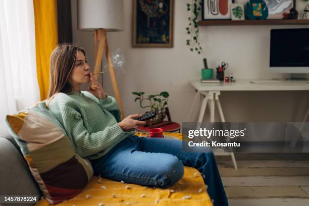 the woman enjoys leisure activities at home, watching tv and smoking joint - smoking weed stock pictures, royalty-free photos & images