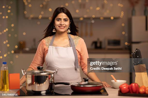 portrait of a young woman cooking food in the kitchen stock photo - housewife stock pictures, royalty-free photos & images