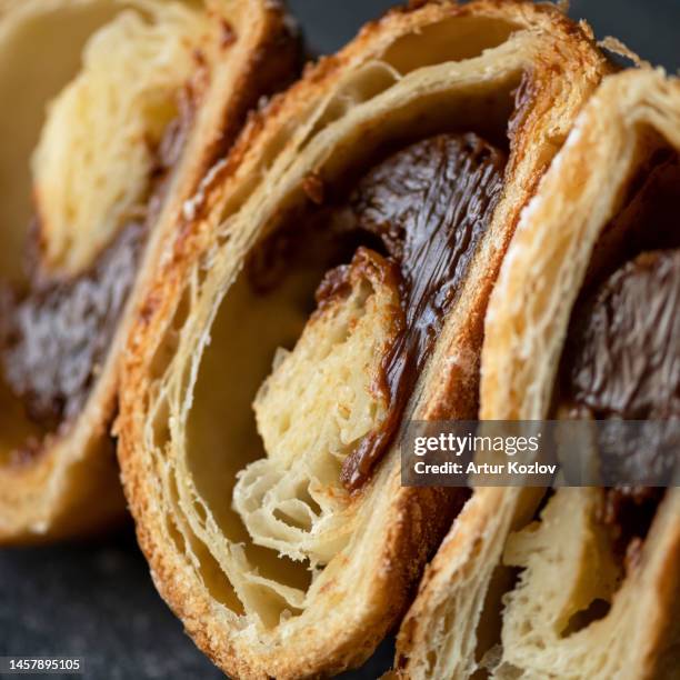 croissant in cut form. puff pastry roll with chocolate filling. french dessert. close-up. soft focus. dark background - puff pastry stock pictures, royalty-free photos & images