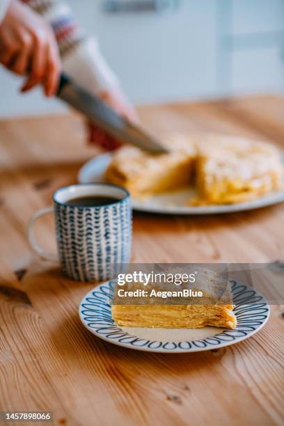 mujer joven preparando el pastel de napoleón para servir - mil hojas fotografías e imágenes de stock