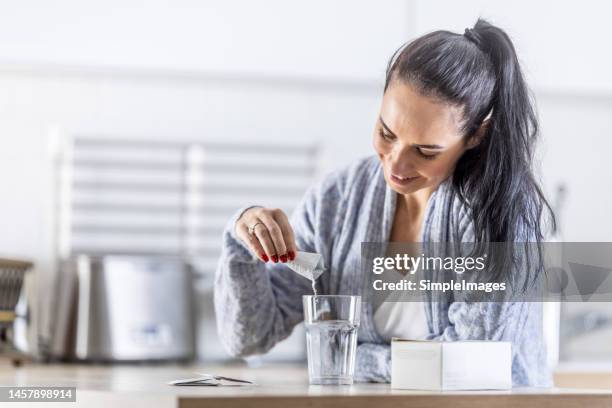 a young woman pours magnesium nutritional supplement into a glass of water. - calcita fotografías e imágenes de stock