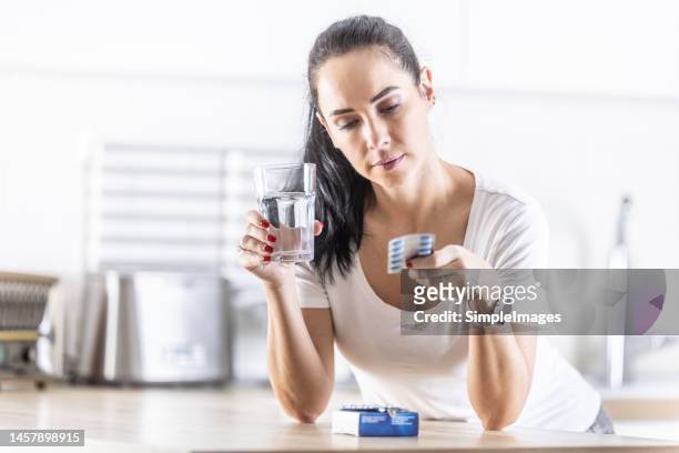 a young woman is studying the instructions about the medicine she will be taking - blister package stock pictures, royalty-free photos & images