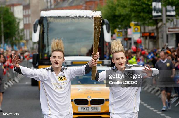 In this handout image provided by LOCOG, Torchbearers 007 John and Edward Grimes, aka Jedward, carry the Olympic Flame on day 19 of the London 2012...