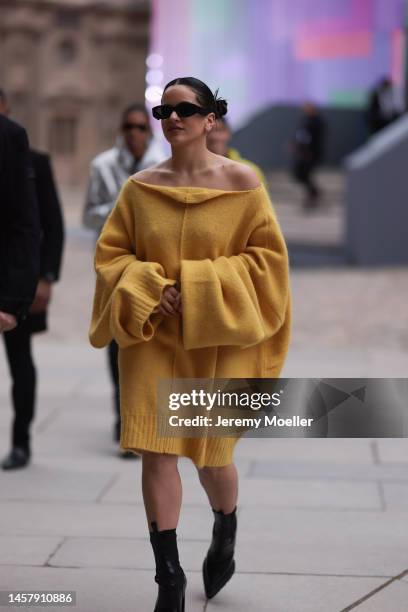 Rosalia seen wearing a yellow R. Simons oversized pullover dress, black Louis Vuitton boots and black sunglasses outside the Louis Vuitton Show...