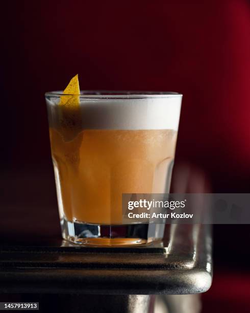 alcoholic citrus drink in glass with foam, decorated with citrus. drink on wooden table. maroon background. soft focus. close-up. side view. copy space - sour taste stock pictures, royalty-free photos & images