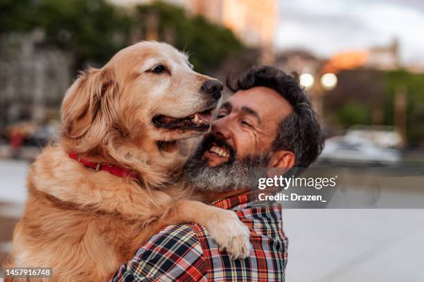 reifer mann mit golden retriever hund, der sich umarmt und liebe teilt - pet equipment stock-fotos und bilder