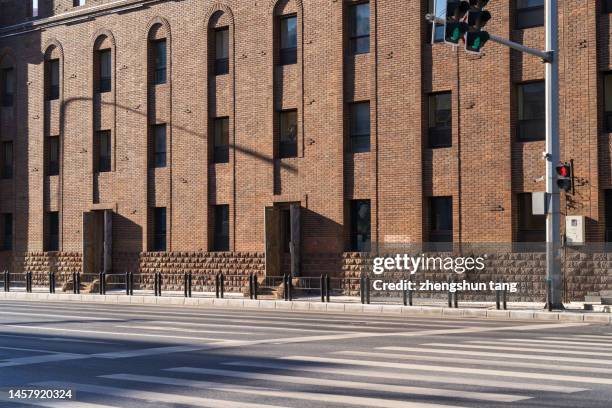 old building with red brick walls on the side of the asphalt road. - traffic light empty road stock pictures, royalty-free photos & images