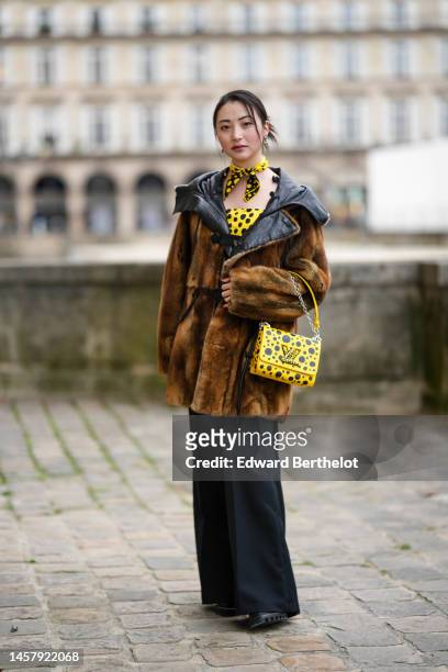 Guest wears silver earrings, a yellow with black and white polka dots print pattern small scarf in collaboration from Yayoi Kusama x Louis Vuitton, a...