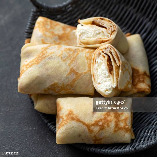 thin pancakes stuffed with cottage cheese on wicker plate. cross-sectional view close-up on dark background - stuffed stock pictures, royalty-free photos & images
