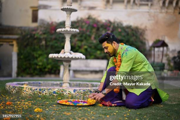 a man with a painted face and plate full of colours and flowers sitting in the courtyard of a palace in rajasthan - traditional festival bildbanksfoton och bilder