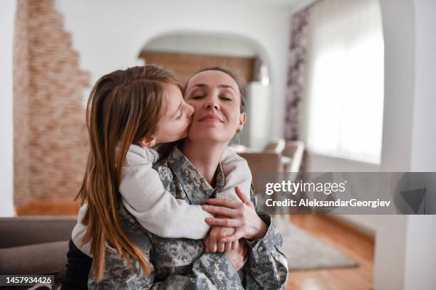 small female child embracing soldier mother and kissing her - armed forces rank stock pictures, royalty-free photos & images