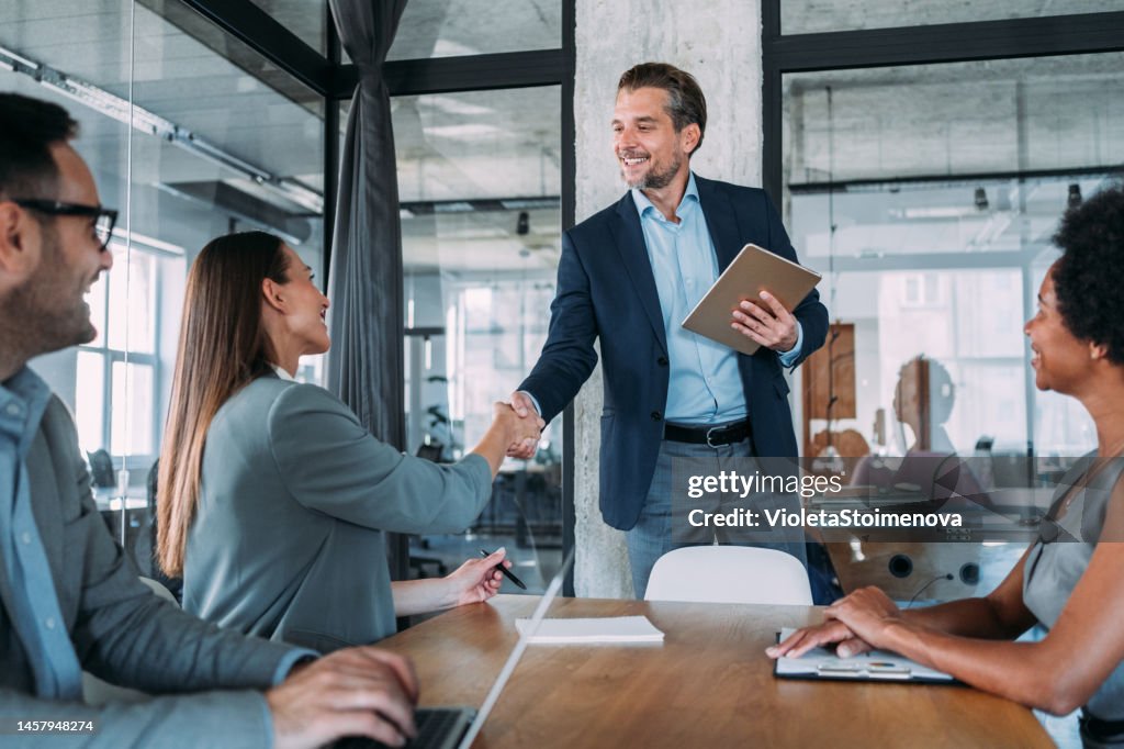Businesswoman and businessman shaking hands across the table.