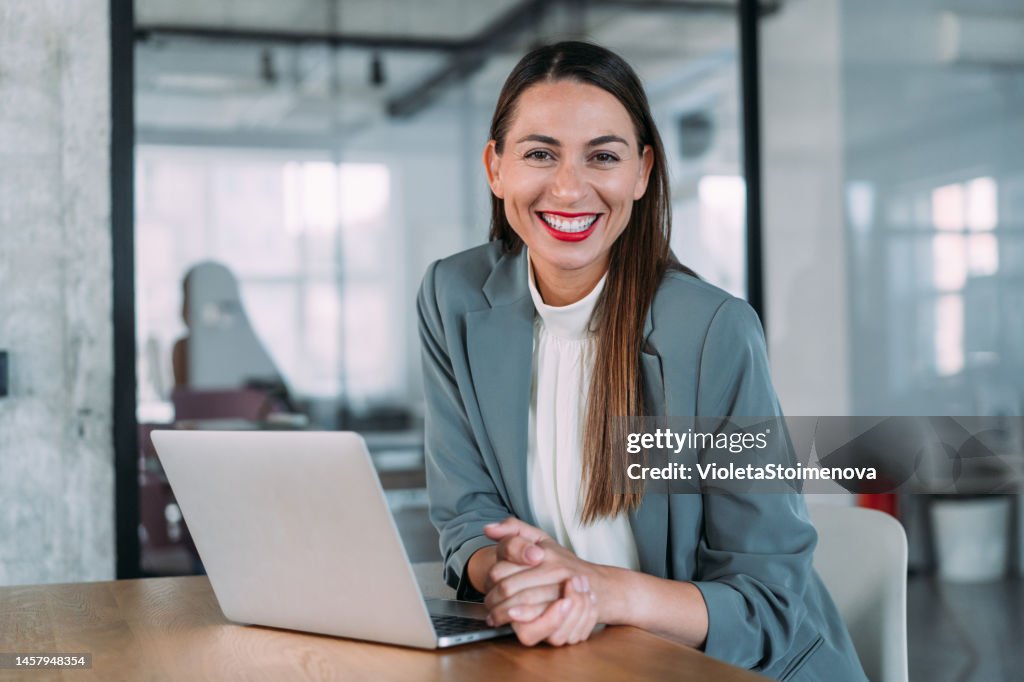 Successful businesswoman in modern office working on laptop.