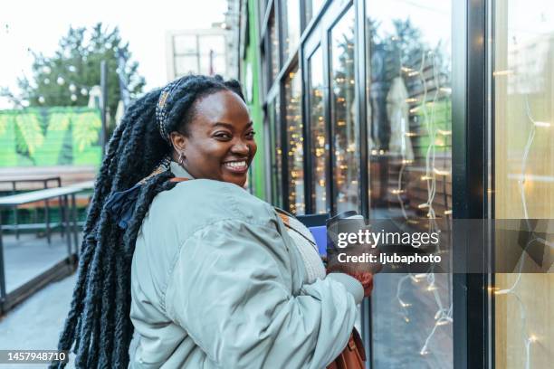 beautiful young african american woman looking behind while walking on street - big city life stock pictures, royalty-free photos & images