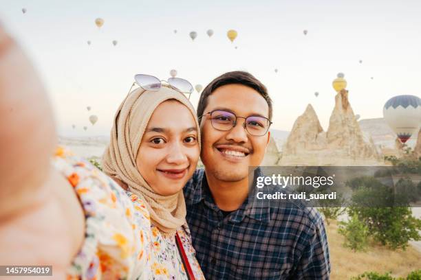 young muslim couple  taking selfie portrait using handphone camera - turkey middle east stockfoto's en -beelden